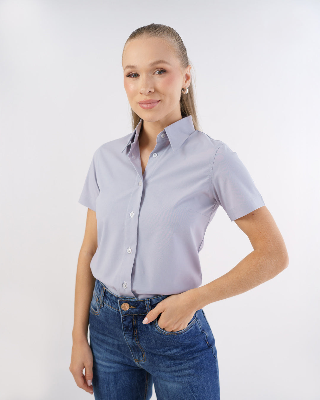 Camisa social feminina manga curta cinza claro vestida por modelo, vista frontal com gola e botoes aparentes