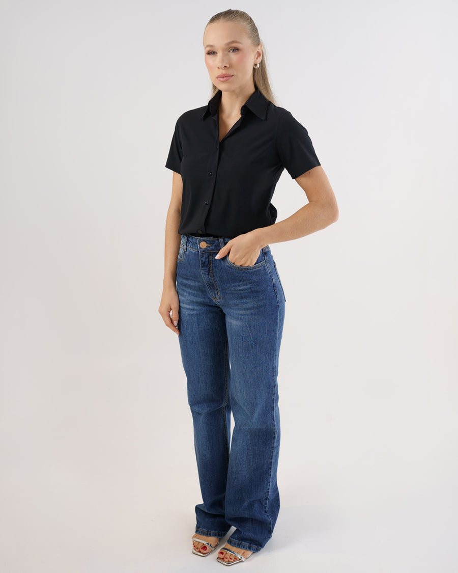 Camisa social feminina manga curta preta em foto de corpo inteiro, modelo combinando com calca jeans azul