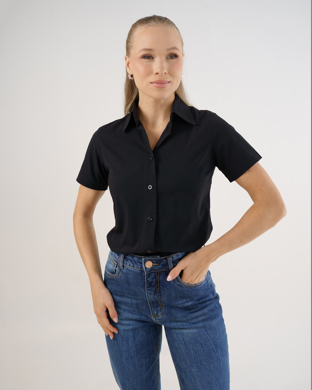 Camisa social feminina manga curta preta vestida por modelo, vista frontal com gola classica e botoes aparentes