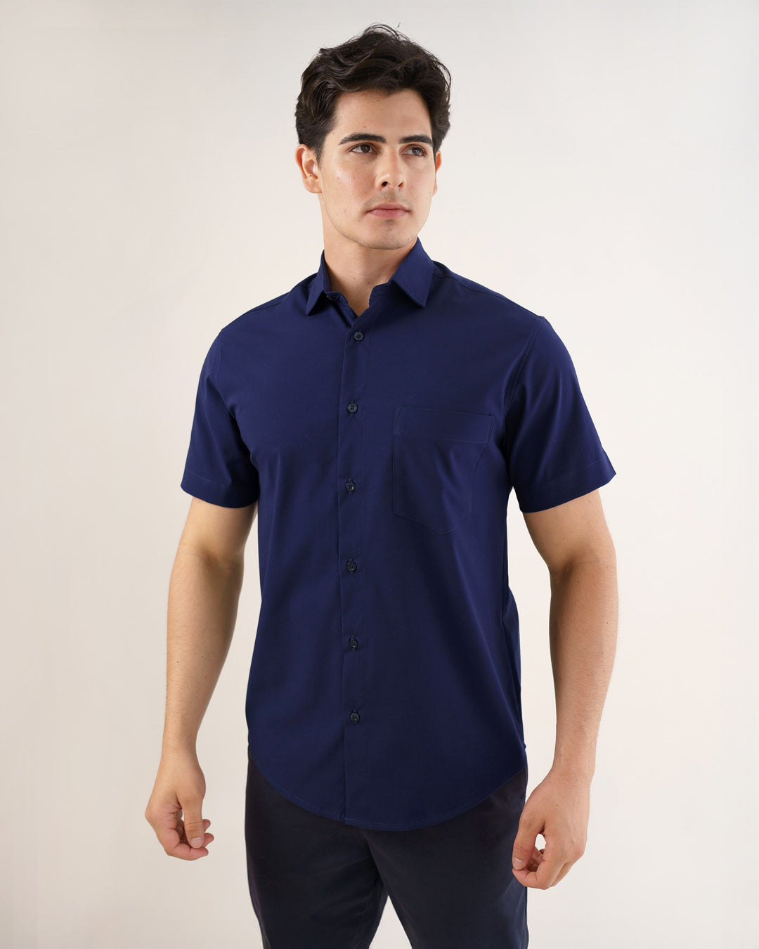 Camisa social masculina manga curta azul marinho vestida por modelo, vista frontal com bolso e botoes aparentes