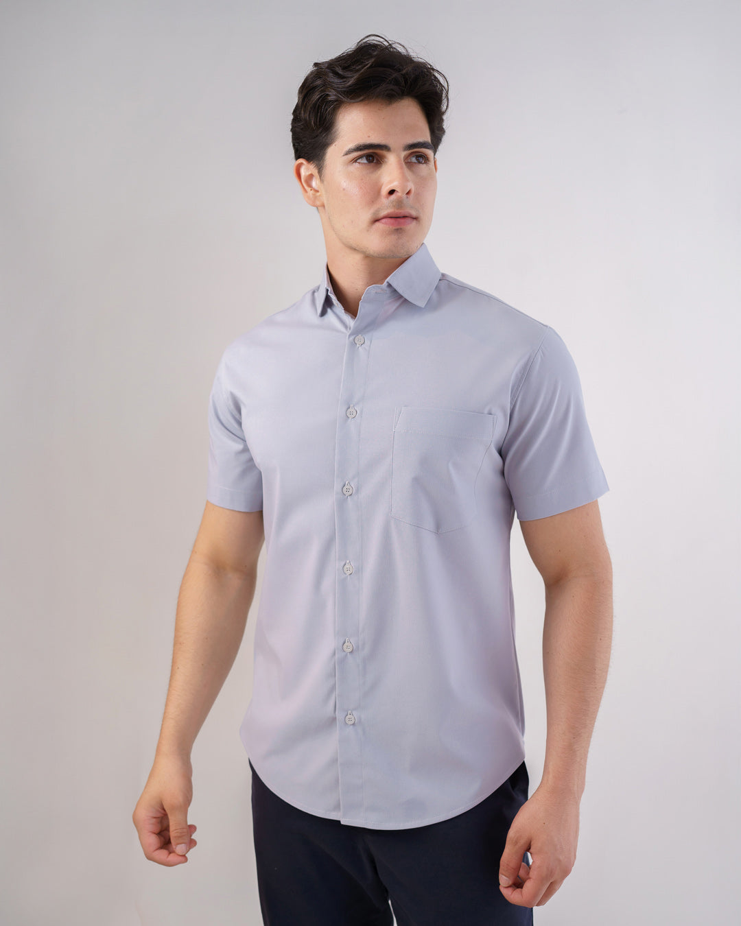 Camisa social masculina manga curta cinza claro vestida por modelo, vista frontal com bolso no peito e botoes