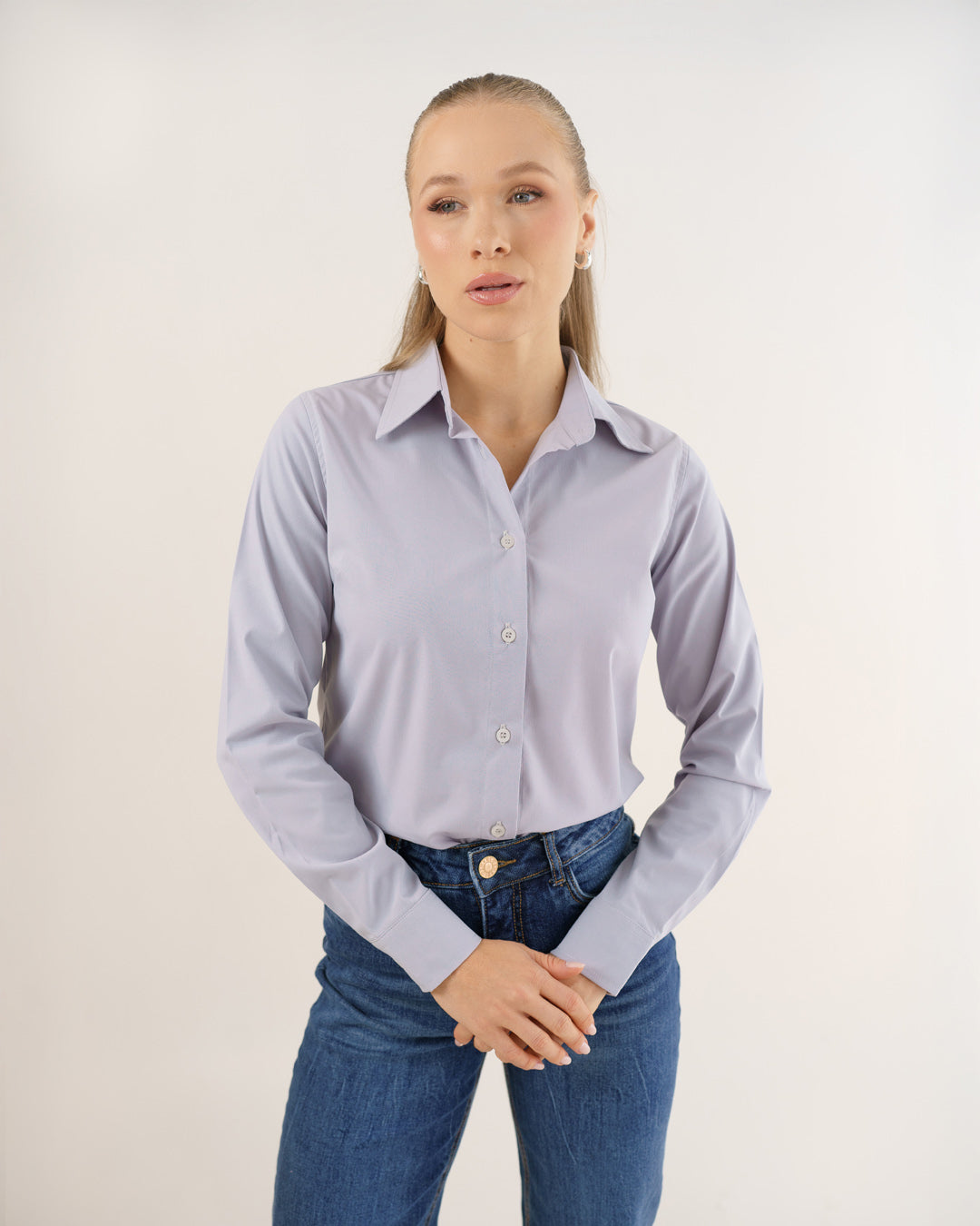 Camisa social feminina manga longa cinza claro vestida por modelo, vista frontal com gola e botoes aparentes