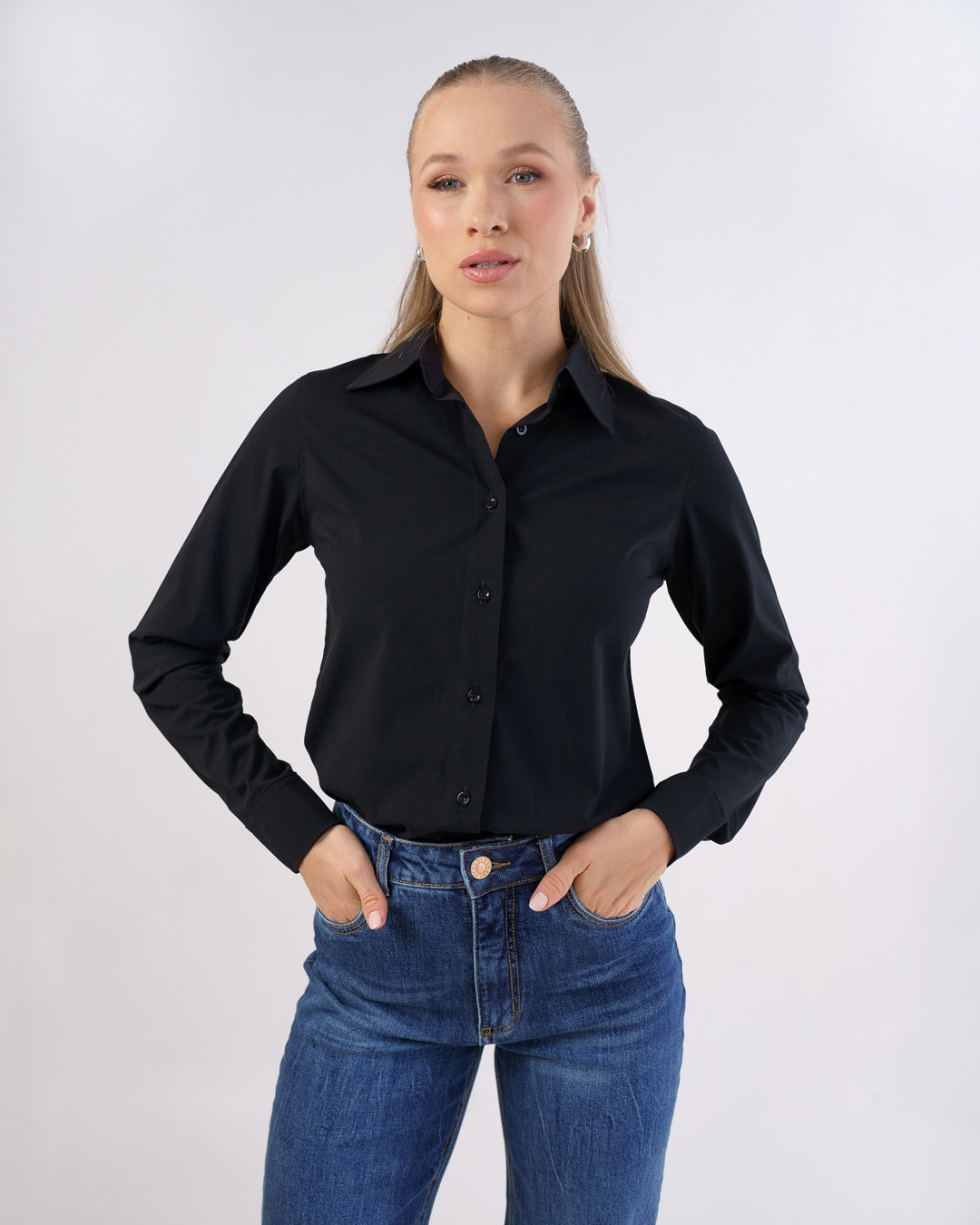 Camisa social feminina manga longa preta em vista frontal, maos nos bolsos mostrando caimento slim e punhos — foto 4