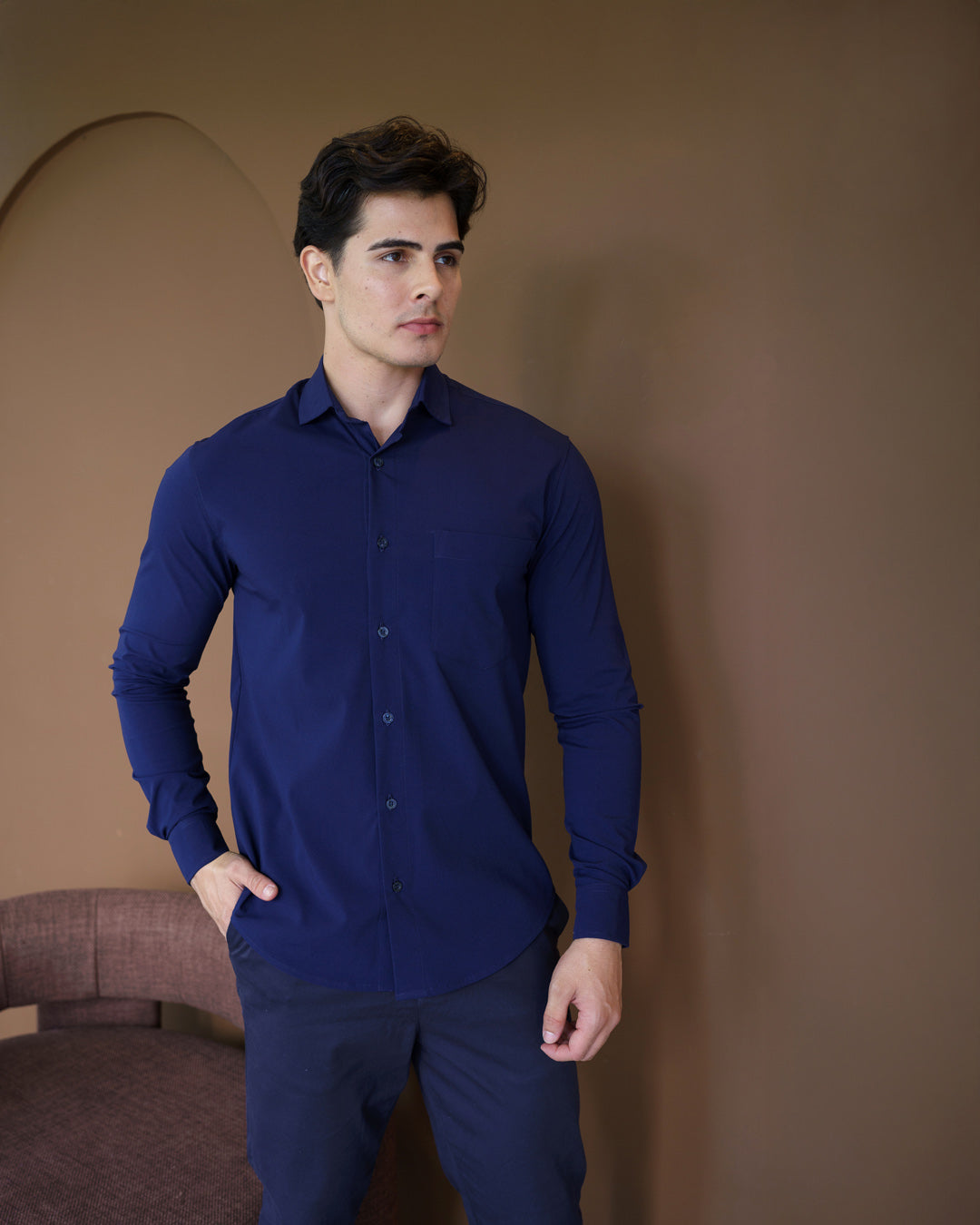 Camisa social masculina manga longa azul marinho em meio corpo frontal, mao no bolso mostrando caimento slim — foto 5