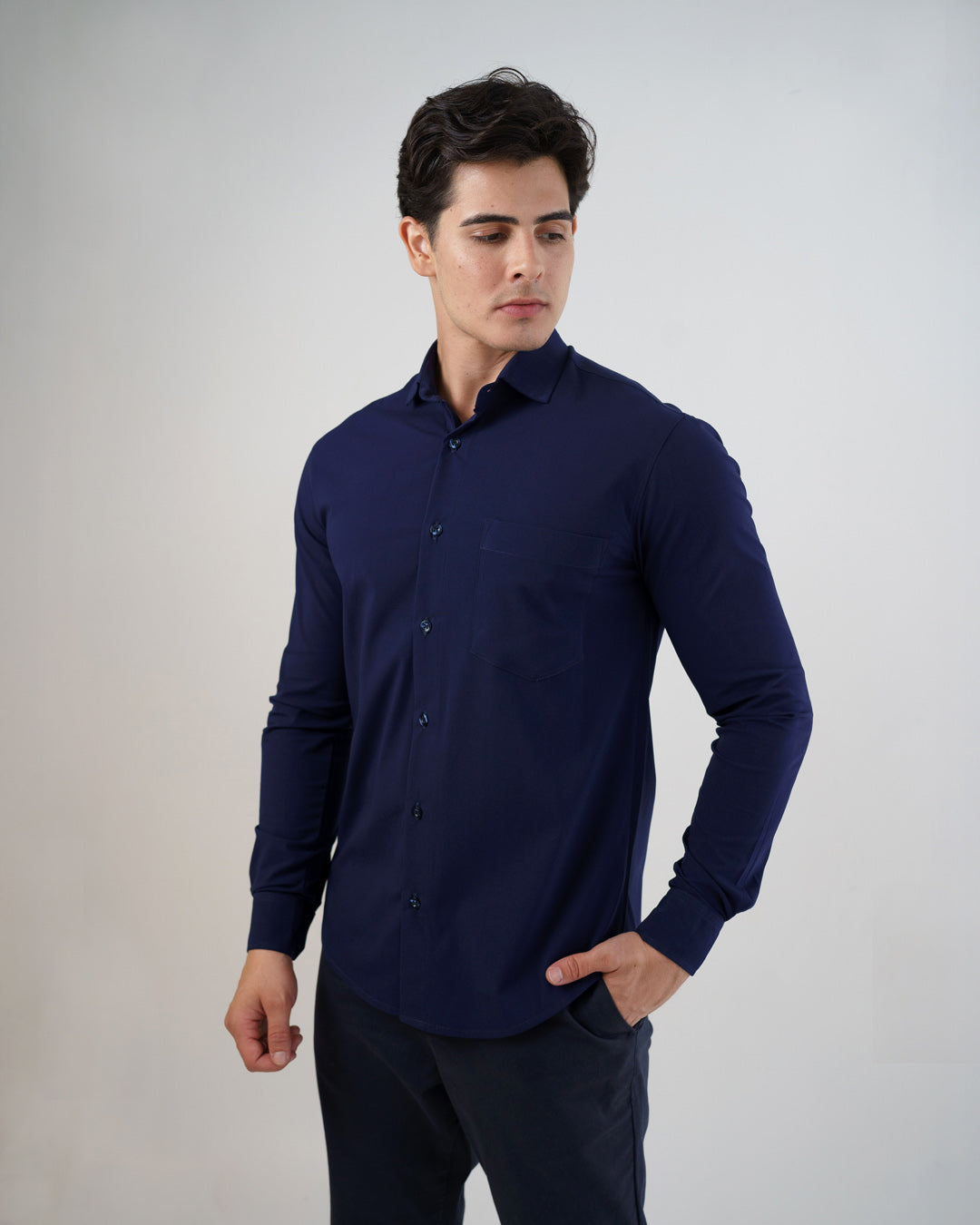 Camisa social masculina manga longa azul marinho vestida por modelo, vista frontal com bolso no peito e botoes
