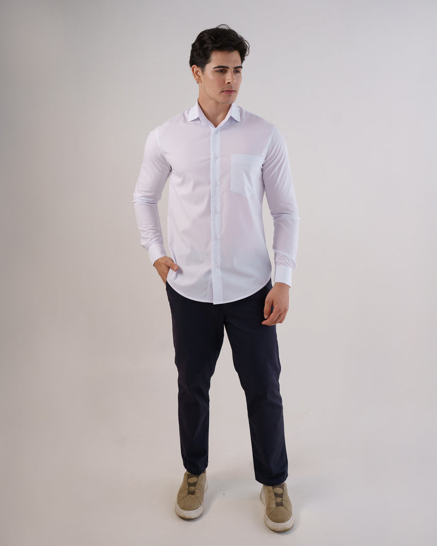 Camisa social masculina manga longa branca em foto de corpo inteiro, mao no bolso da calca azul escura