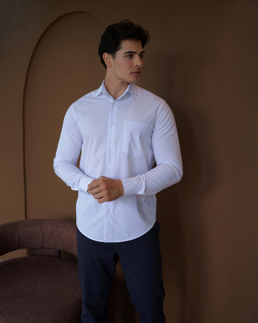 Camisa social masculina manga longa branca em meio corpo frontal, ajustando o punho com bolso no peito visivel