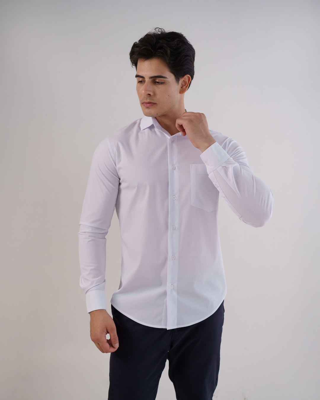 Camisa social masculina manga longa branca vestida por modelo, vista frontal ajustando a gola com bolso no peito