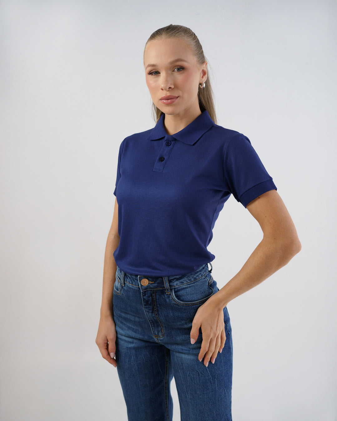 Camiseta polo feminina premium azul marinho, vista frontal com gola e dois botões, modelo veste com jeans