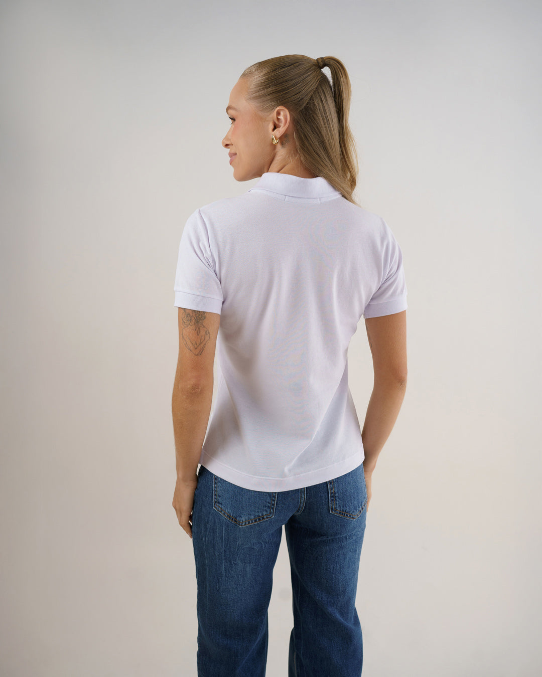 Camiseta polo feminina premium branca, vista de costas mostrando caimento reto e gola esportiva — foto 5