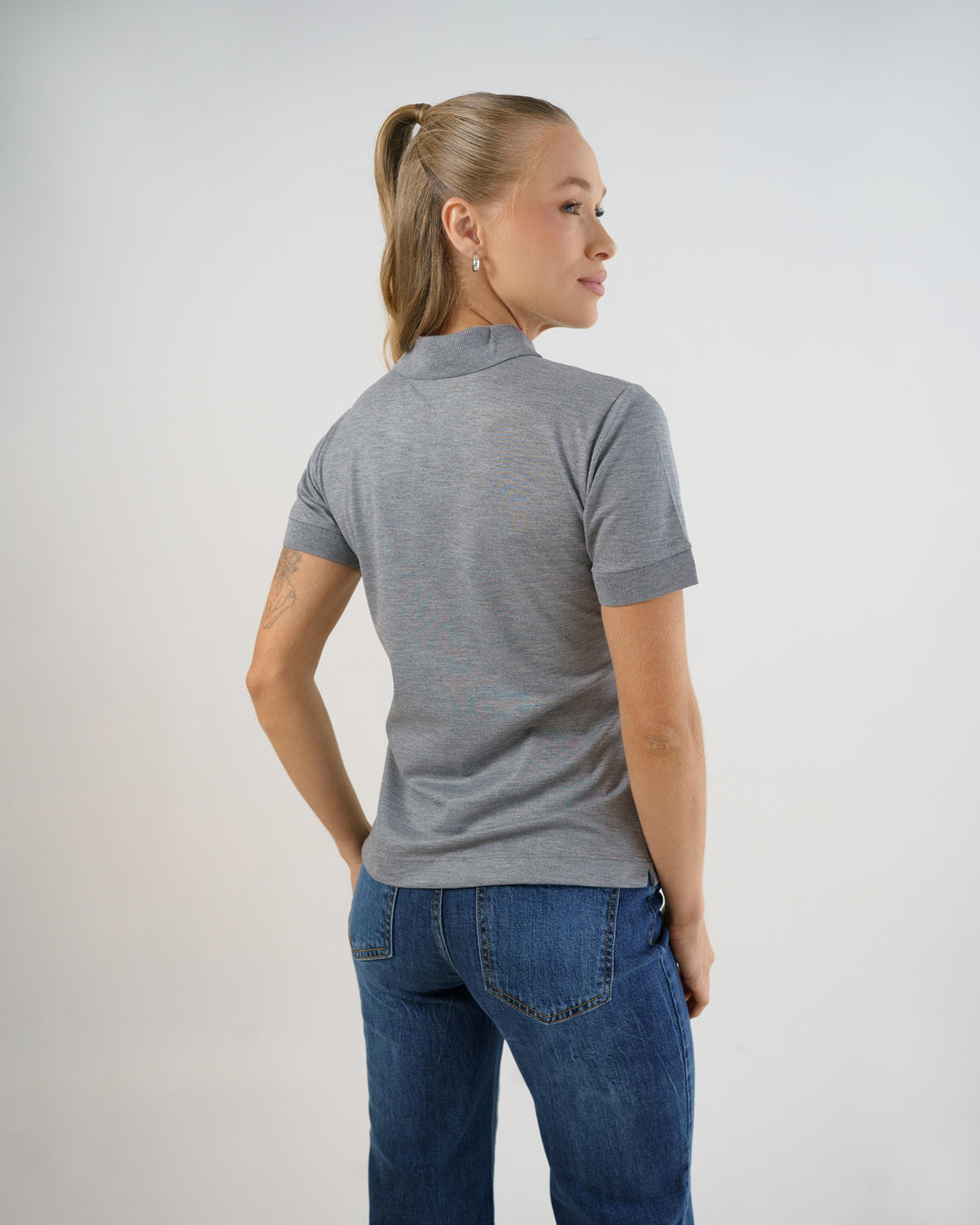 Camiseta polo feminina premium cinza claro, vista de costas mostrando caimento ajustado e punhos canelados — foto 5