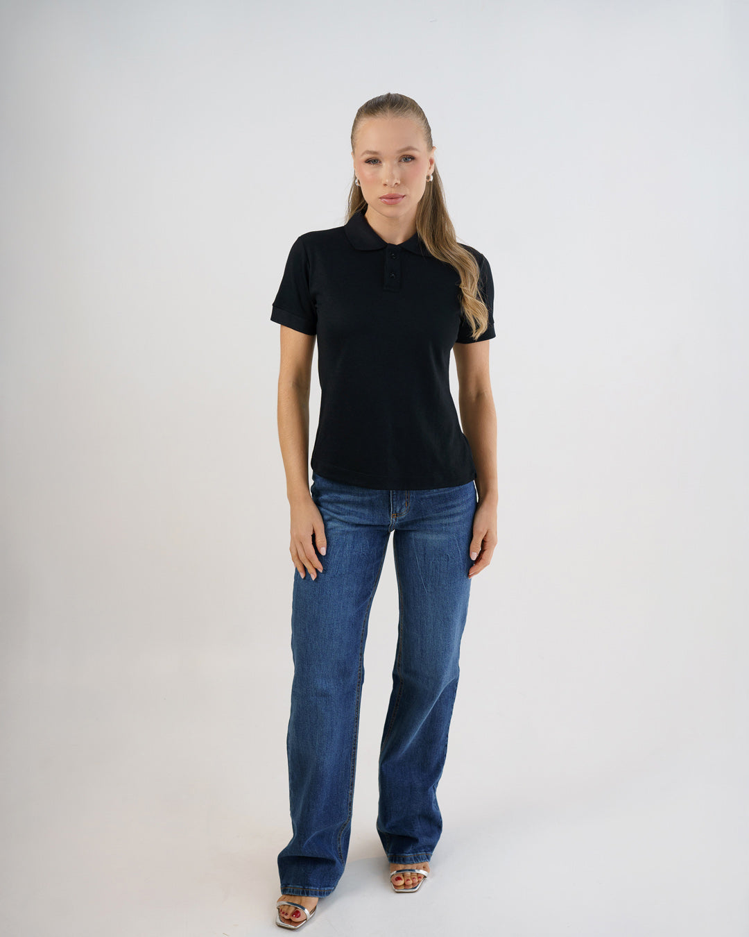 Camiseta polo feminina premium preta em corpo inteiro, modelo veste a polo com calça jeans azul — foto 5