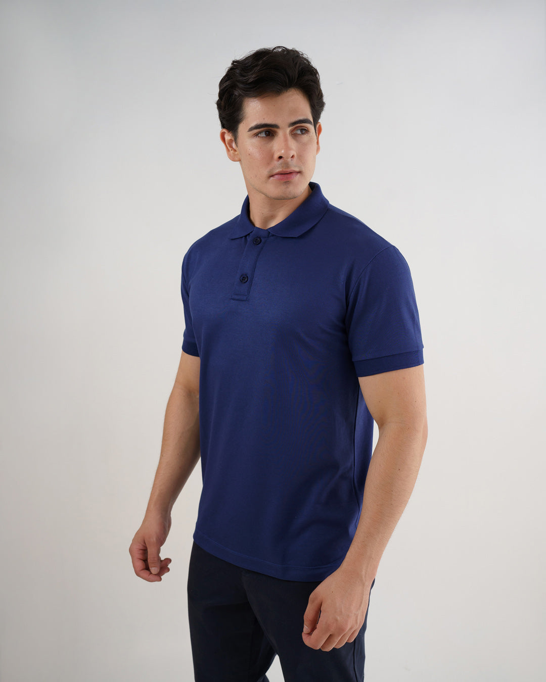 Camiseta polo masculina premium azul marinho em meio corpo de leve perfil, com gola e dois botões