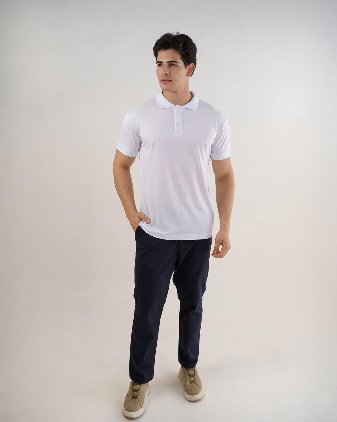 Camiseta polo masculina premium branca em foto de corpo inteiro, combinada com calça azul-marinho e tênis — foto 3
