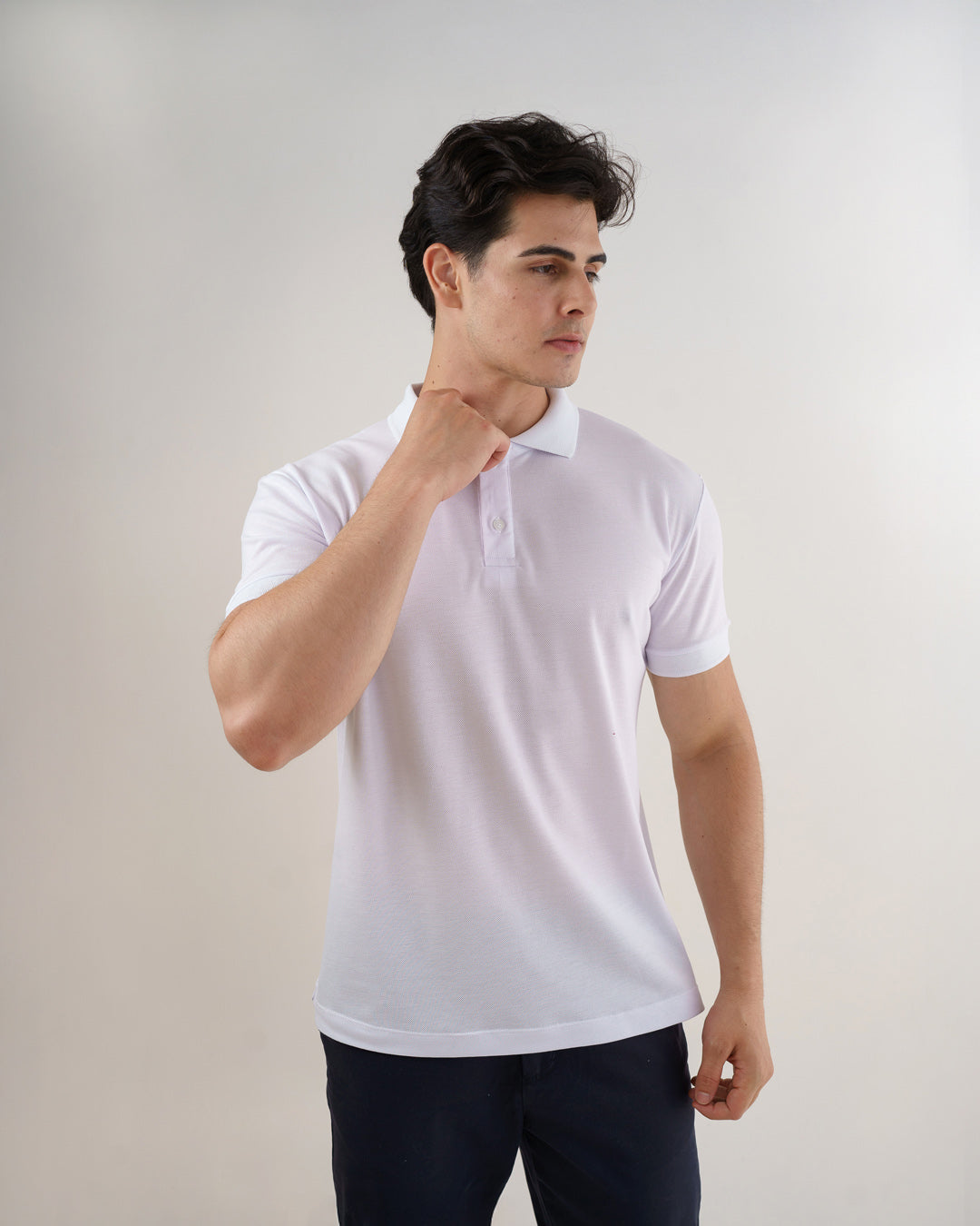 Camiseta polo masculina premium branca em meio corpo, modelo com a mão junto à gola destacando o colarinho — foto 5