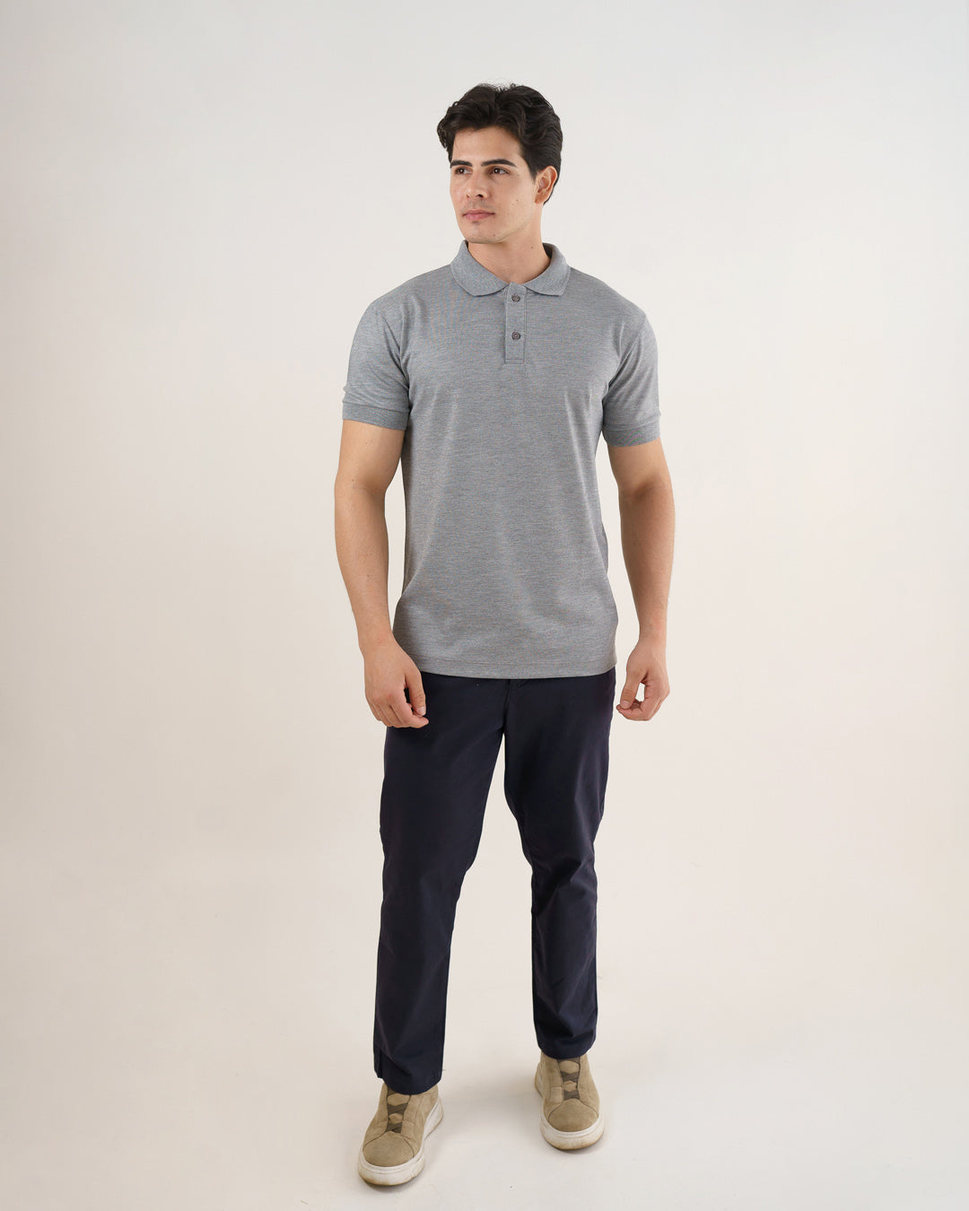 Camiseta polo masculina premium cinza claro de frente em corpo inteiro, com calça azul-marinho e tênis — foto 2