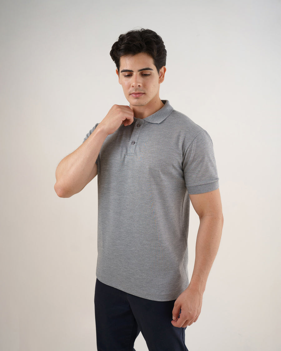 Camiseta polo masculina premium cinza claro em meio corpo, modelo com a mão junto à gola e dois botões