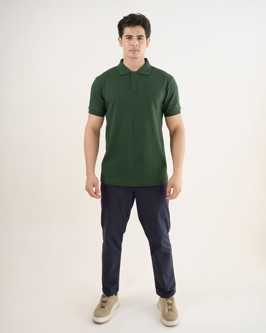 Camiseta polo masculina premium verde musgo de frente em corpo inteiro, caimento reto sobre calça azul-marinho
