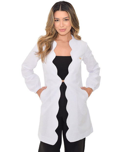 Jaleco feminino Aurora branco em meio corpo frontal, com borda ondulada, pin dourado e mãos nos bolsos