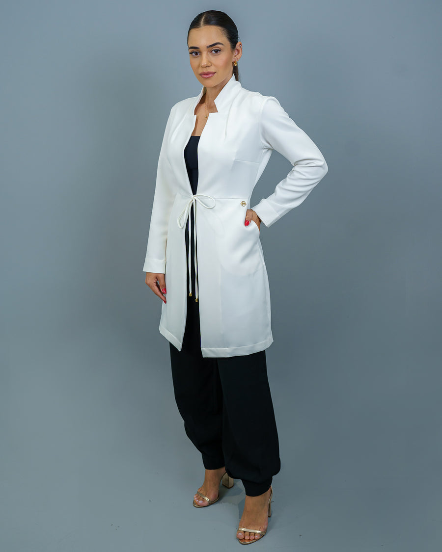 Jaleco feminino Clarice com manga off white de corpo inteiro, modelo com mão no bolso e amarração frontal