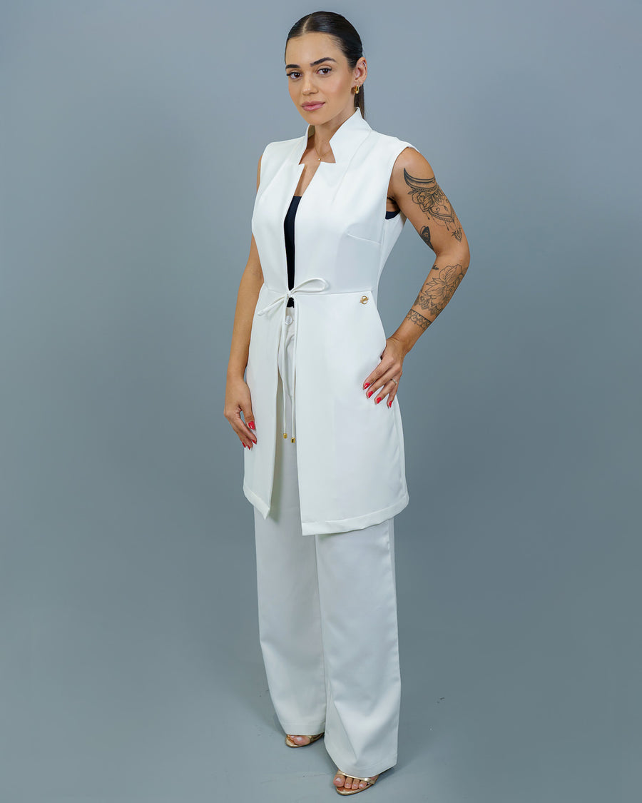 Jaleco feminino Clarice sem manga off white de corpo inteiro, modelo com mãos na cintura mostrando o caimento