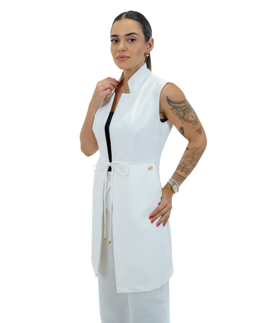 Jaleco feminino Clarice sem manga off white em vista lateral, modelo segurando a gola alta estruturada
