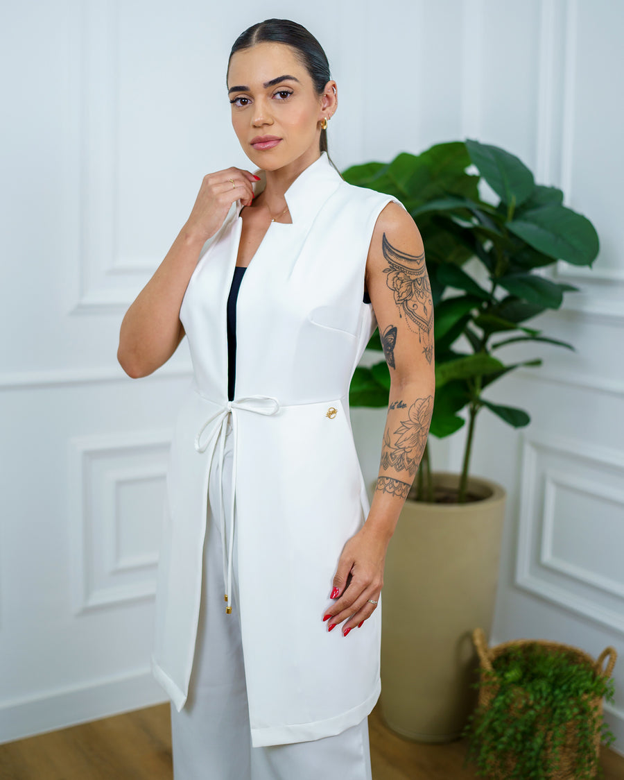 Jaleco feminino Clarice sem manga off white em vista lateral, com gola estruturada e amarração na cintura