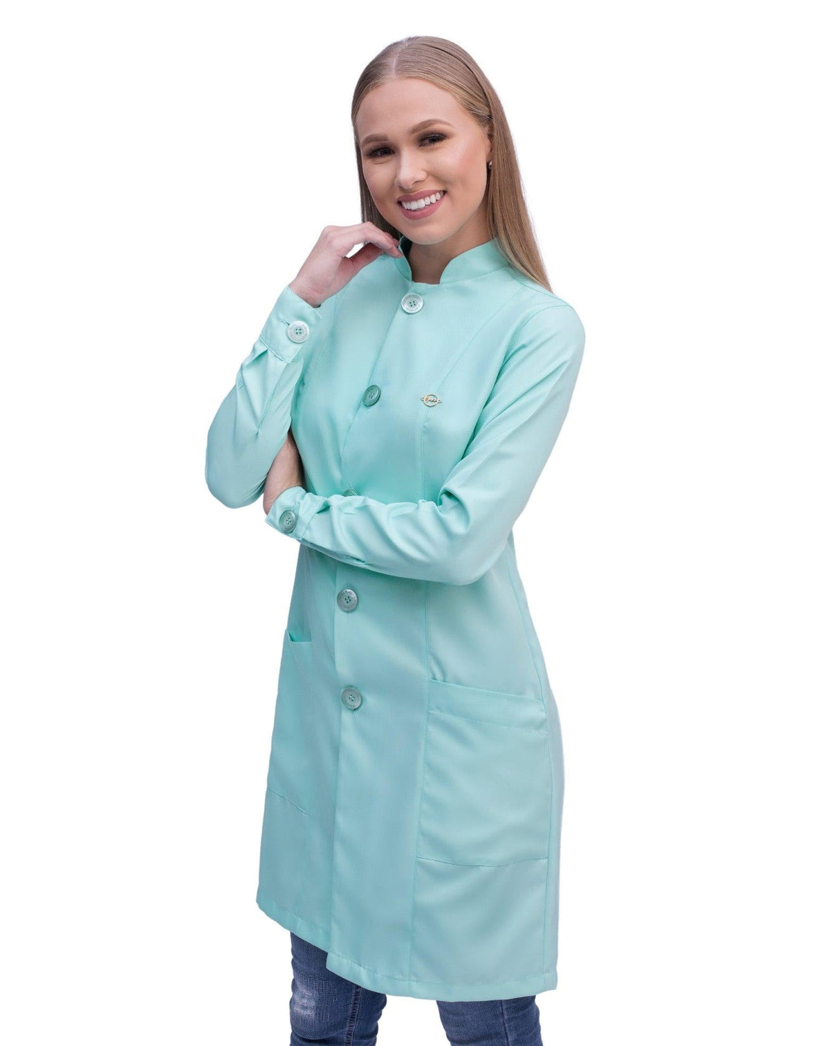 Jaleco feminino Diamond verde água de lado em modelo sorrindo, destaque para punho com botão perolado e pin dourado — foto 4