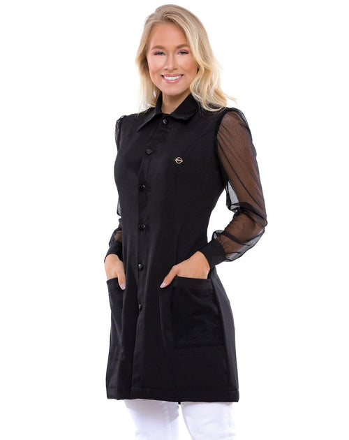Jaleco feminino Jasmine preto em foto frontal, modelo com as mãos nos bolsos e mangas de tela transparente