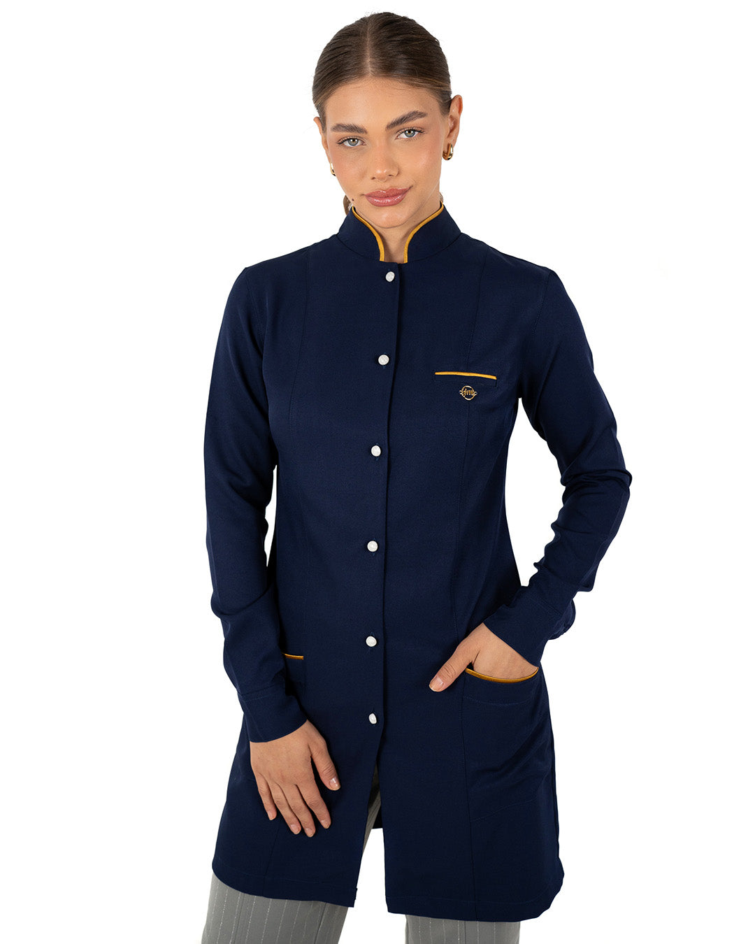 Jaleco feminino Slim Charm Color azul marinho de frente, modelo com as mãos nos bolsos de viés dourado — foto 3