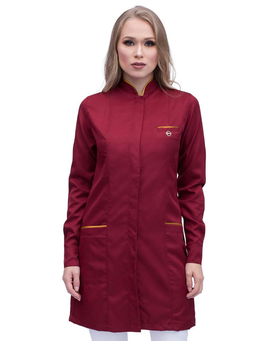 Jaleco feminino Slim Premium vinho bordô com viés dourado, vista frontal em modelo, gola padre e bolsos com friso