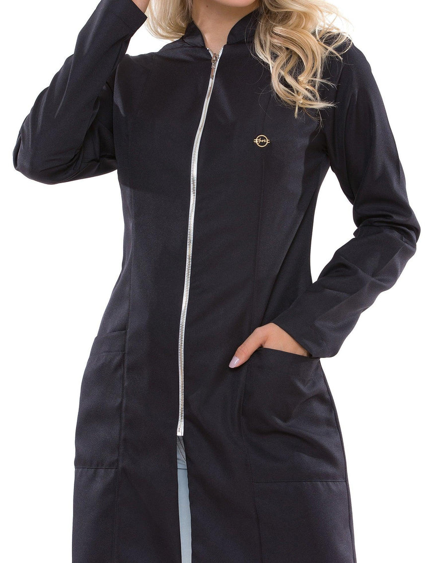 Jaleco feminino Smooth preto em close frontal, detalhe do zíper prateado, pin dourado e bolso com mão apoiada