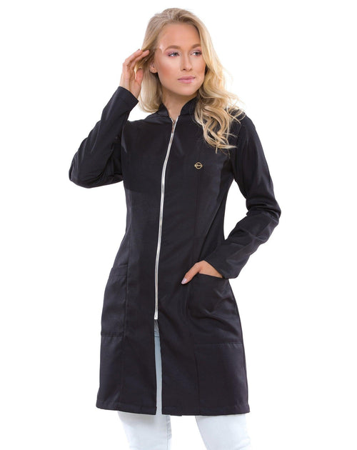 Jaleco feminino Smooth preto com zíper prateado, vista frontal em modelo, pin dourado no peito e bolsos frontais