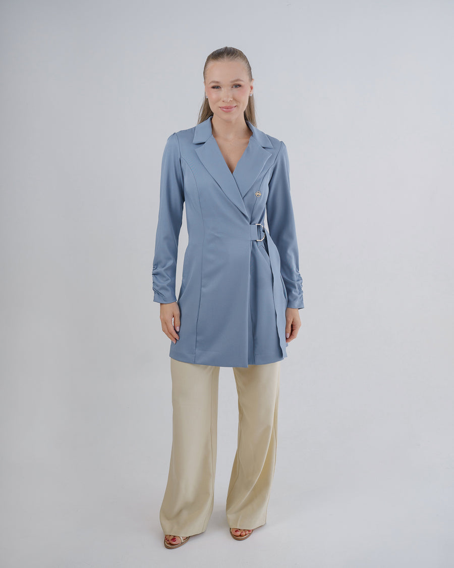 Jaleco feminino Sofia azul grafite de corpo inteiro em fundo neutro, frente transpassada com fivela regulável