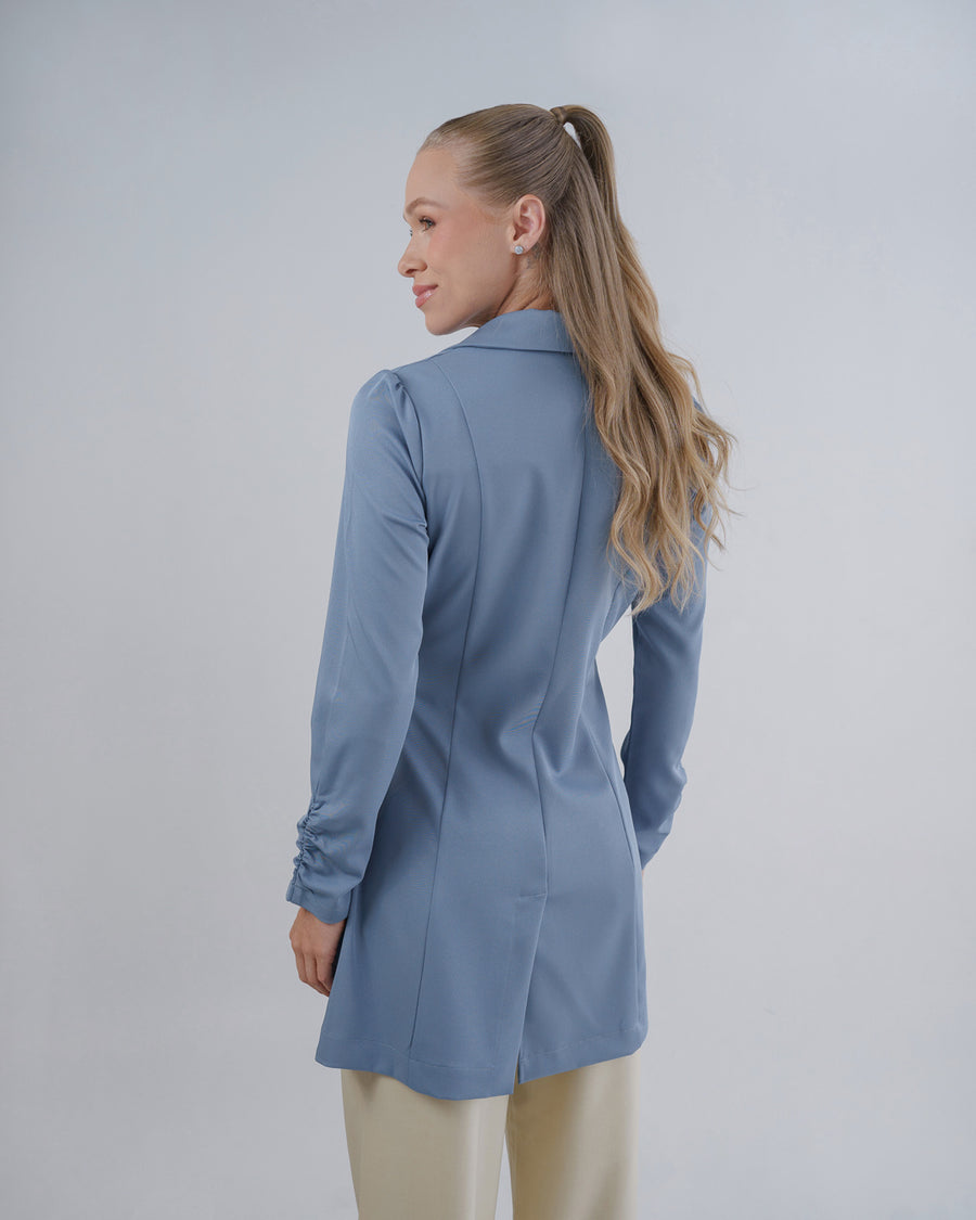 Jaleco feminino Sofia azul grafite visto de costas em modelo, recortes acinturados e mangas com franzido no punho