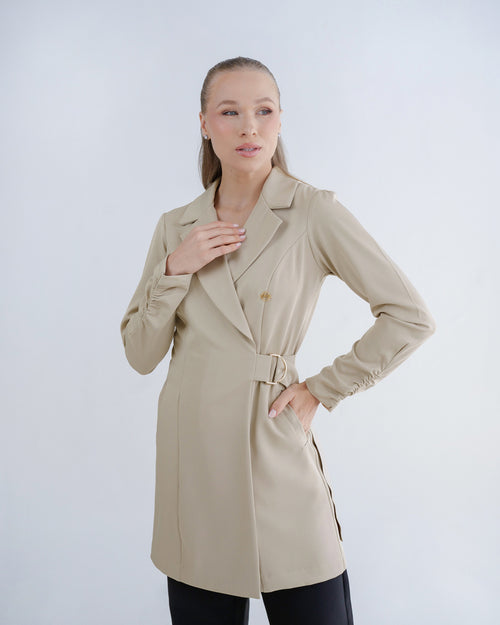 Jaleco feminino Sofia bege, vista frontal em modelo, gola de blazer transpassada e fivela dourada na cintura