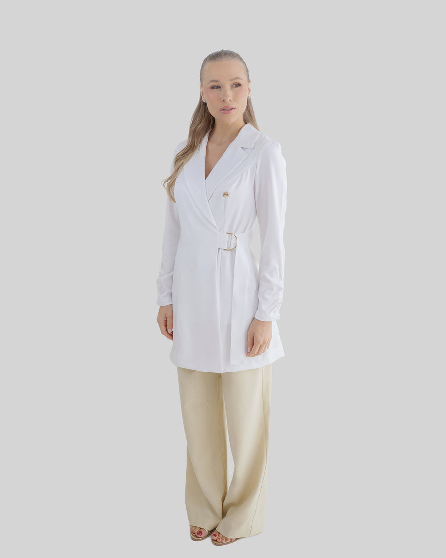 Jaleco feminino Sofia branco em vista lateral de corpo inteiro, fivela dourada na cintura e caimento fluido