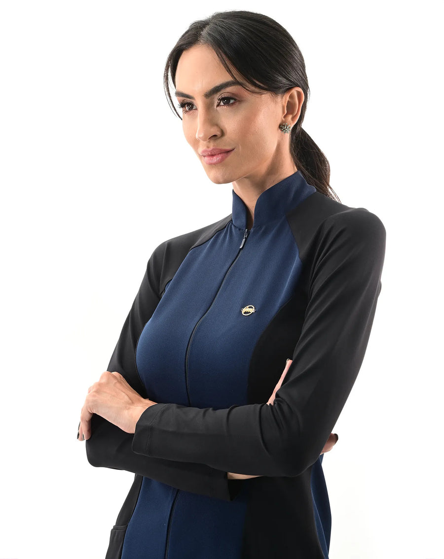 Jaleco feminino Vicky azul marinho com preto em detalhe da gola alta e zíper, modelo de lado com braços cruzados
