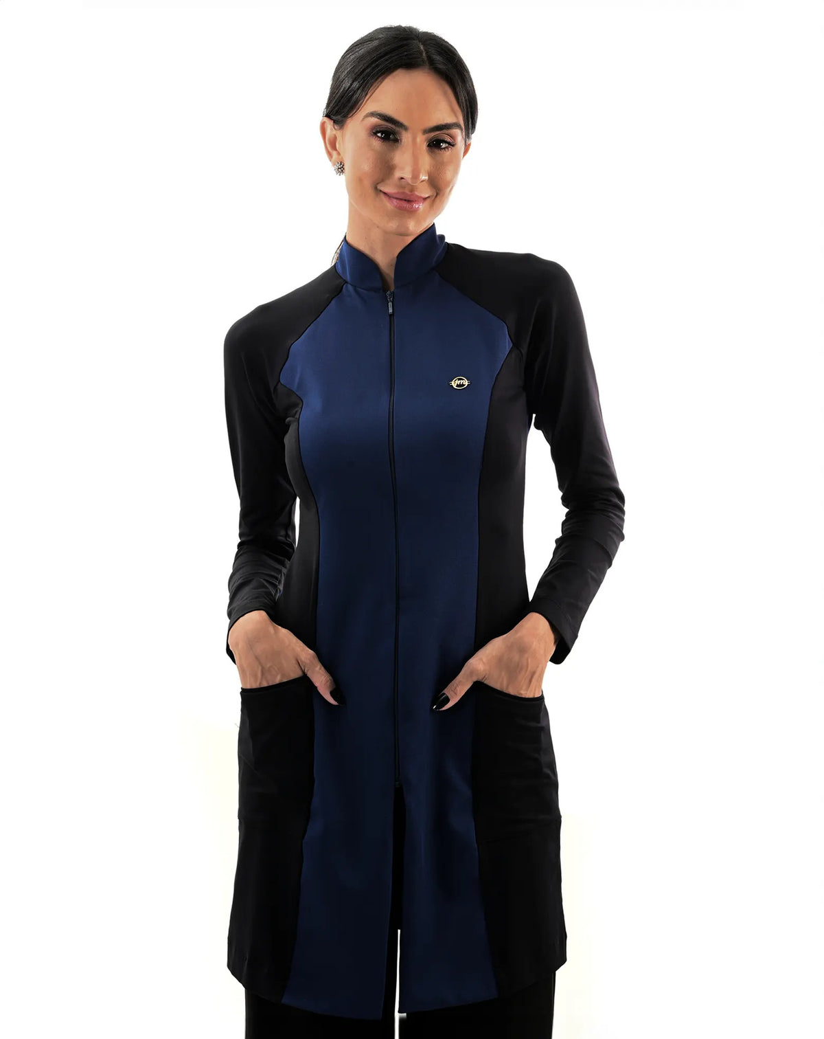 Jaleco feminino Vicky azul marinho com preto de frente, gola alta com zíper, modelo com as mãos nos bolsos frontais