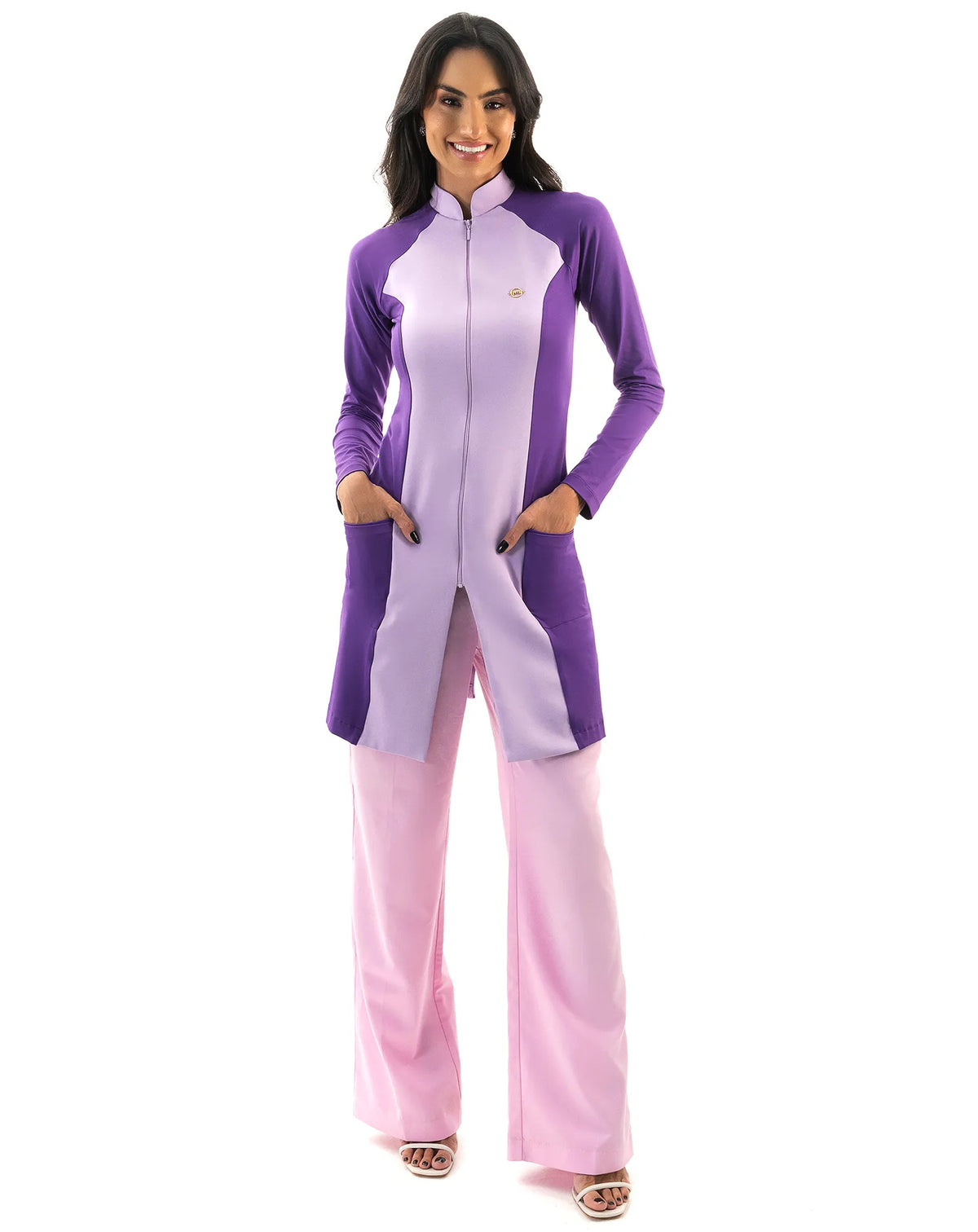 Jaleco feminino Vicky lavanda com roxo de corpo inteiro, modelo de frente com as mãos nos bolsos roxos