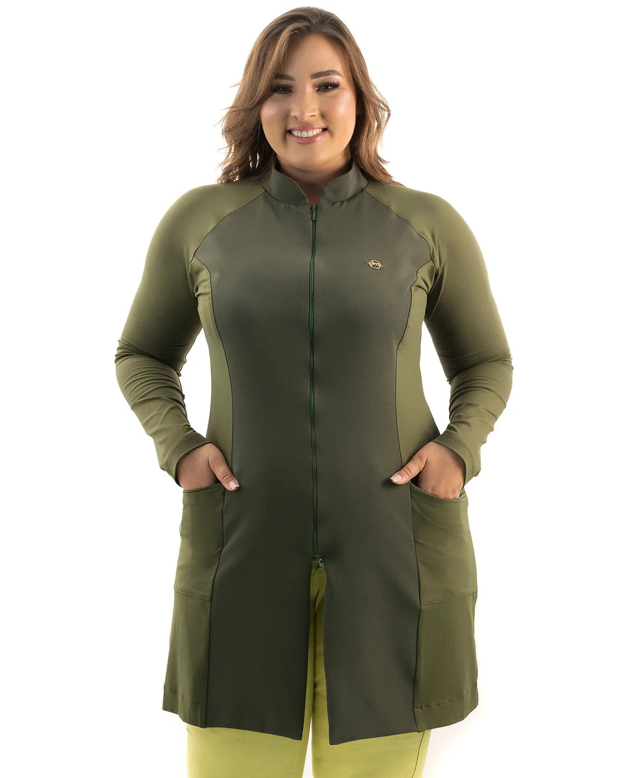 Jaleco feminino Vicky verde militar em modelo plus size de frente, com as mãos nos bolsos e zíper frontal