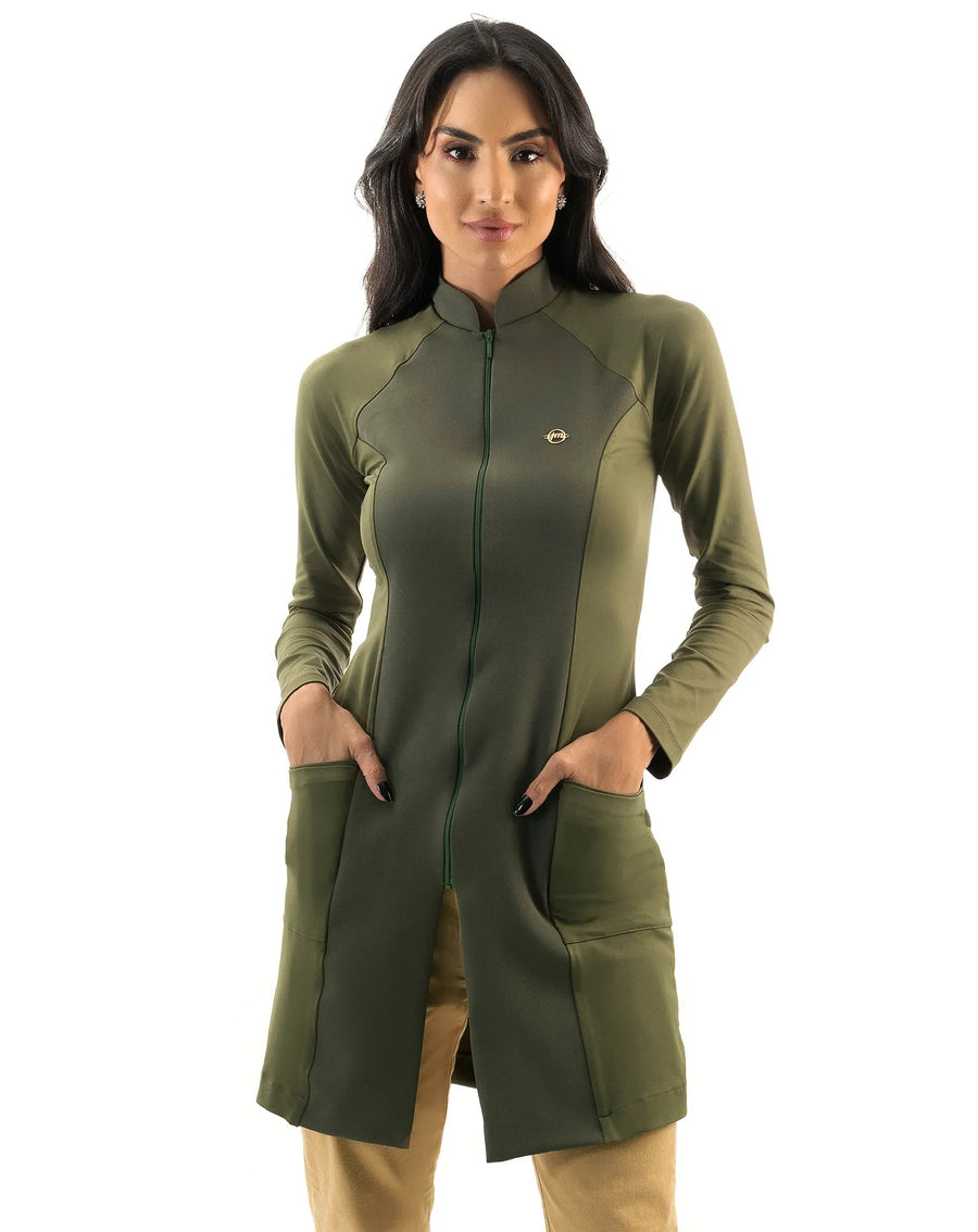 Jaleco feminino Vicky verde militar de frente, gola alta com zíper e pin dourado, mãos nos bolsos frontais
