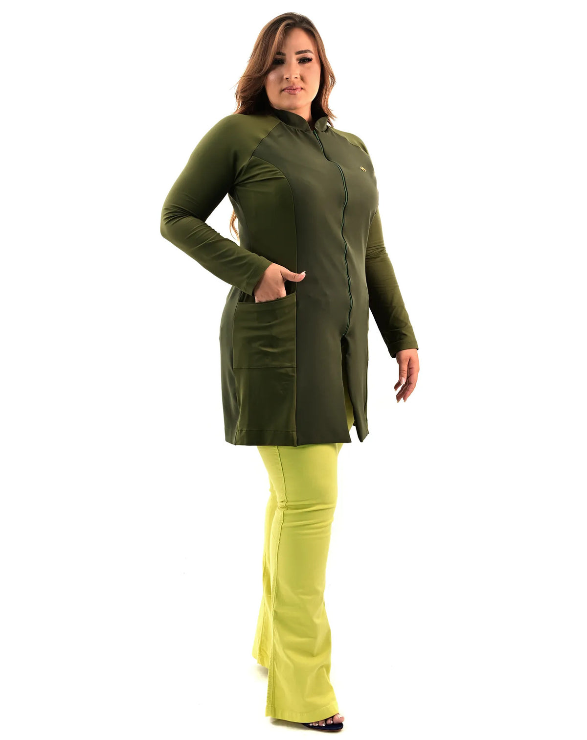 Jaleco feminino Vicky verde militar de lado em modelo plus size, mão no bolso lateral e calça verde clara — foto 5