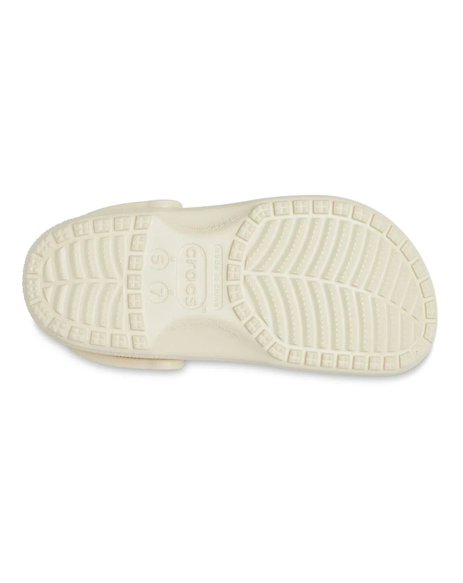 Detalhe do solado da Sandália Crocs Classic Clog Bone com relevo antiderrapante e logo Crocs no centro