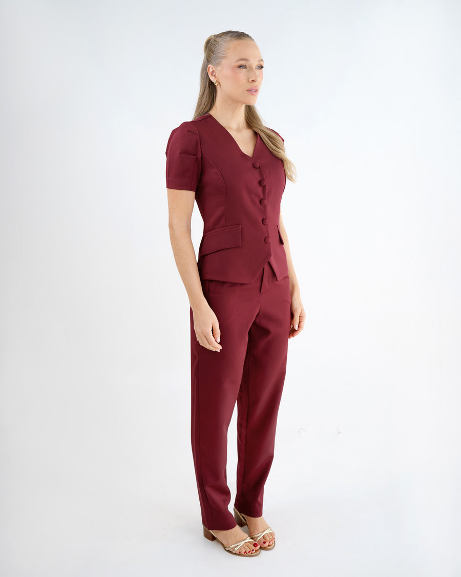 Scrub feminino Classic bordô de lado em corpo inteiro, mostrando o caimento da blusa e da calça reta