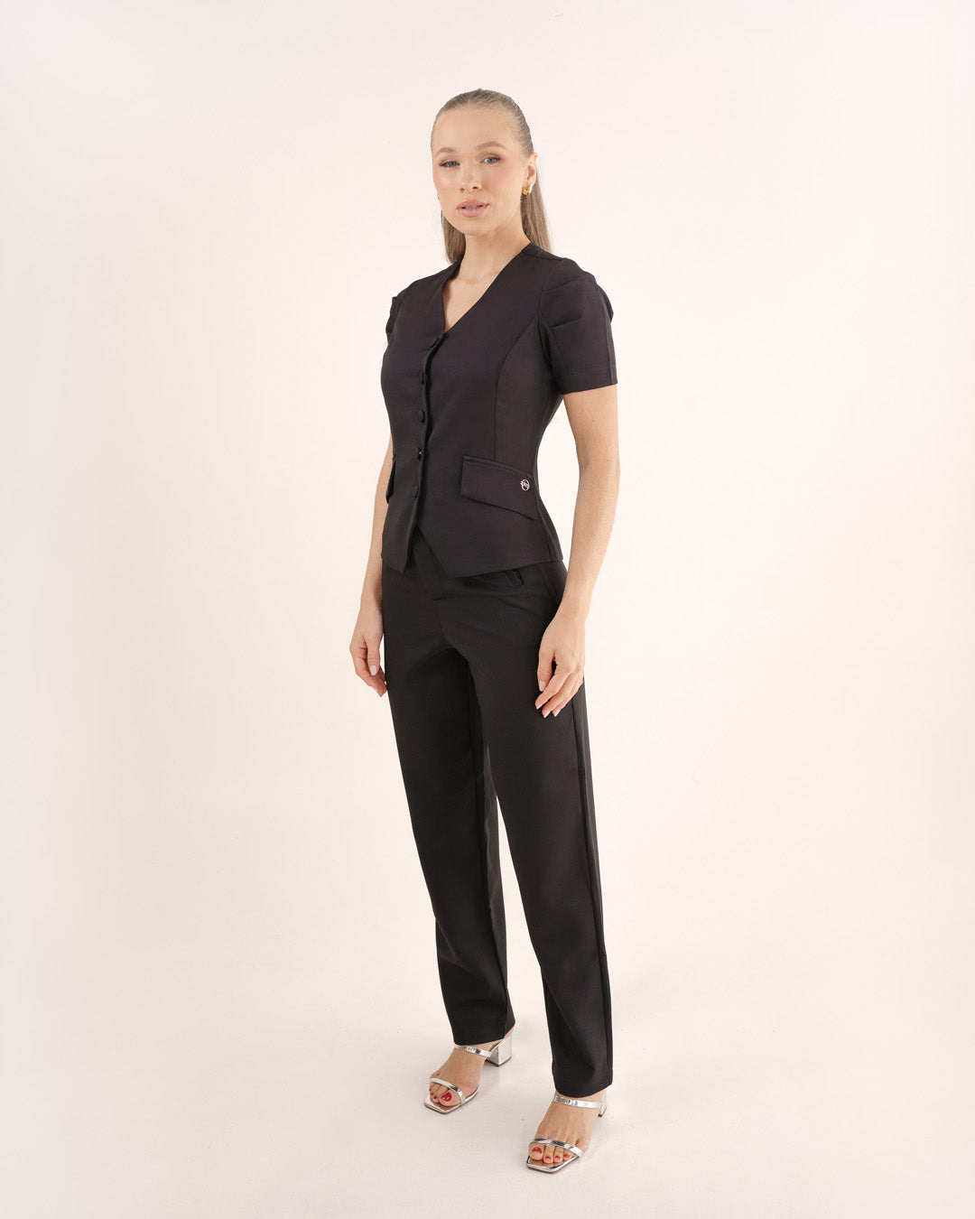 Scrub feminino Classic preto de lado em corpo inteiro, blusa acinturada com bolso de lapela e calça reta — foto 5