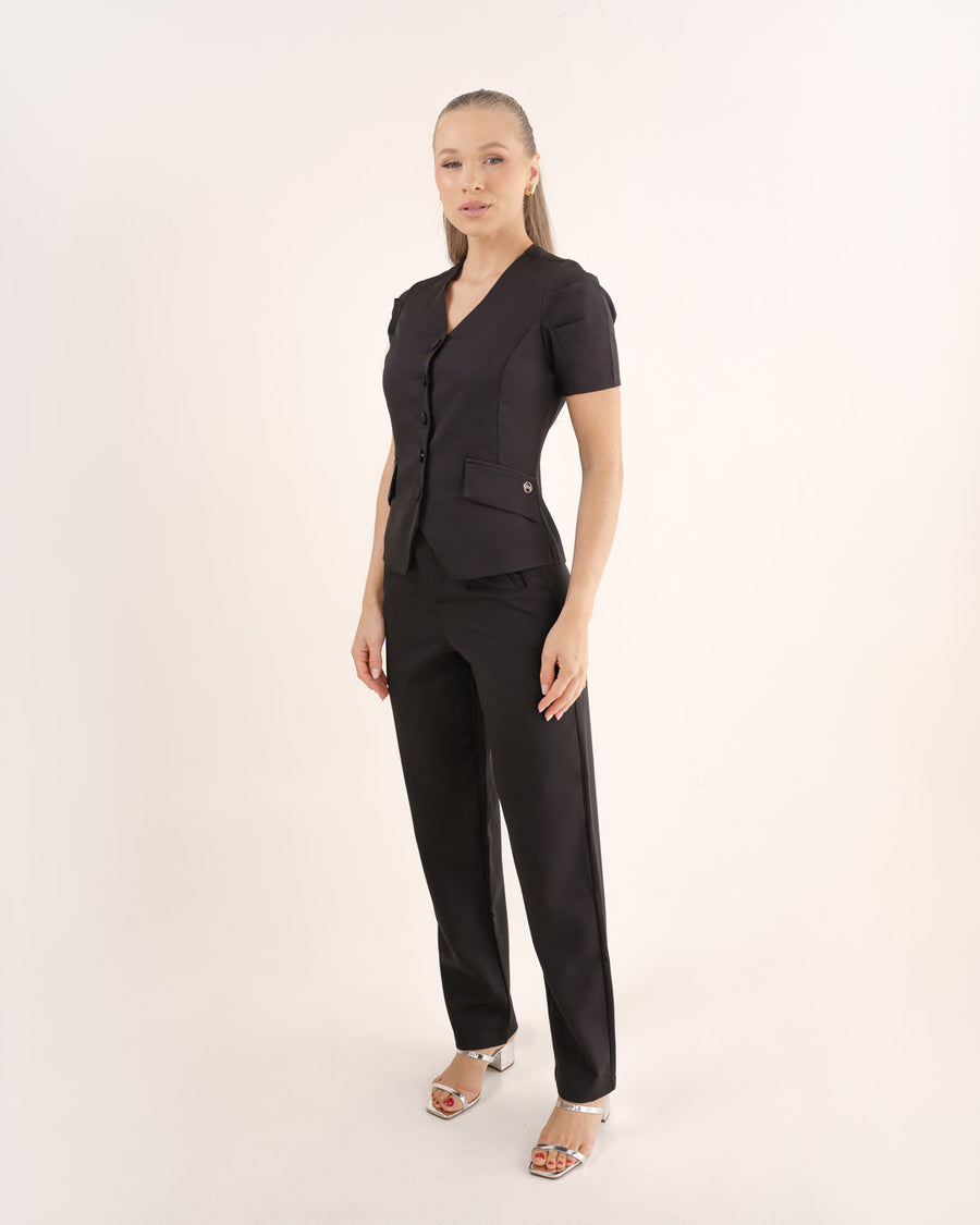 Scrub feminino Classic preto de lado em corpo inteiro, blusa acinturada com bolso de lapela e calça reta