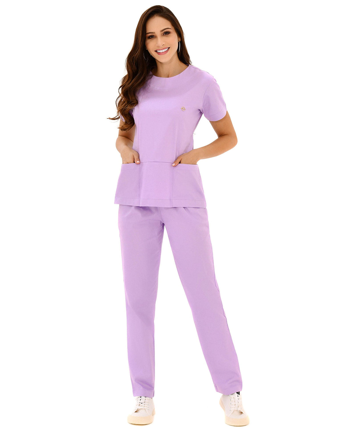 Scrub feminino Confort lilás de frente em corpo inteiro, modelo com as mãos nos bolsos frontais da blusa
