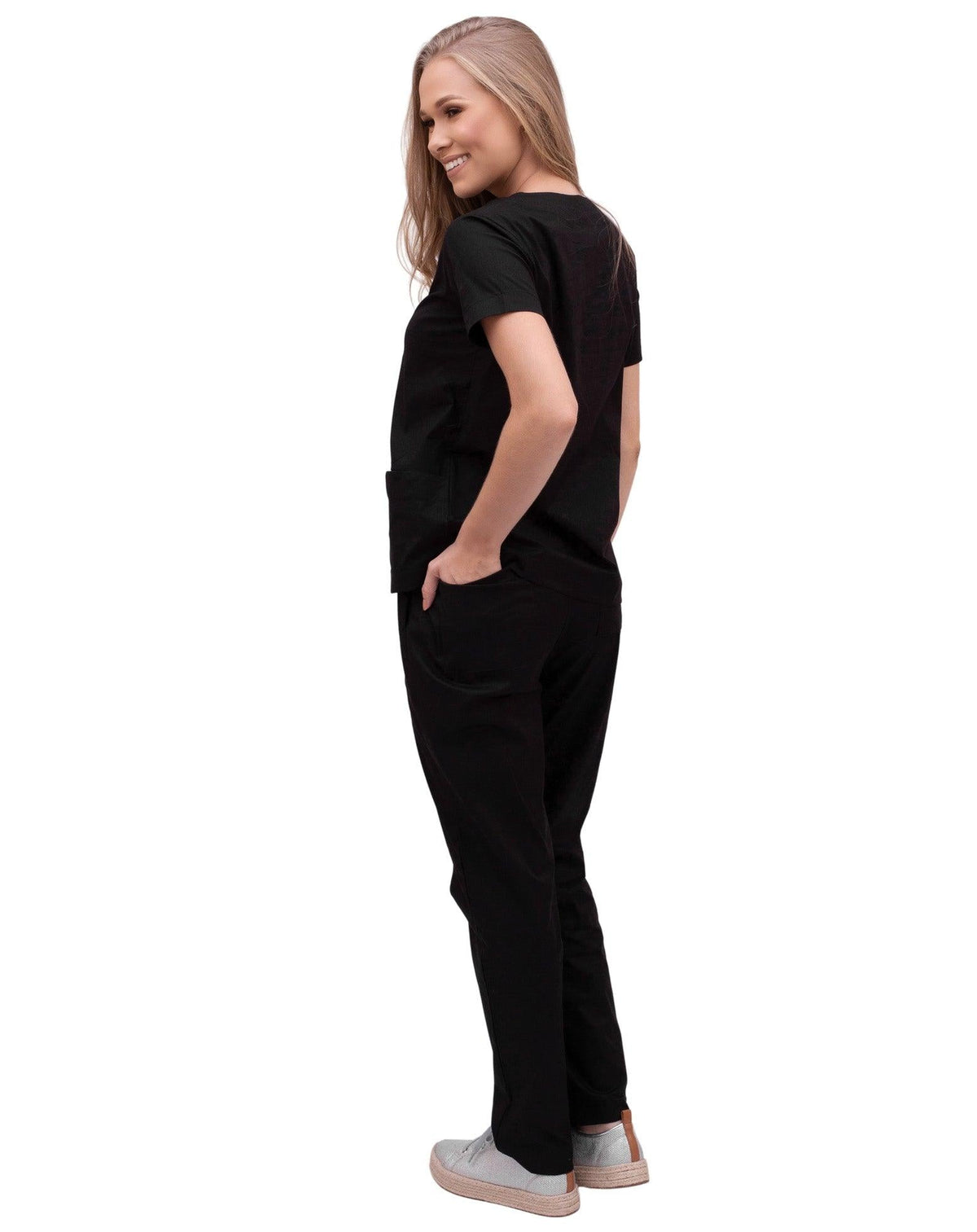Scrub feminino Confort preto de costas, modelo com a mão no bolso da calça e caimento solto da blusa — foto 4