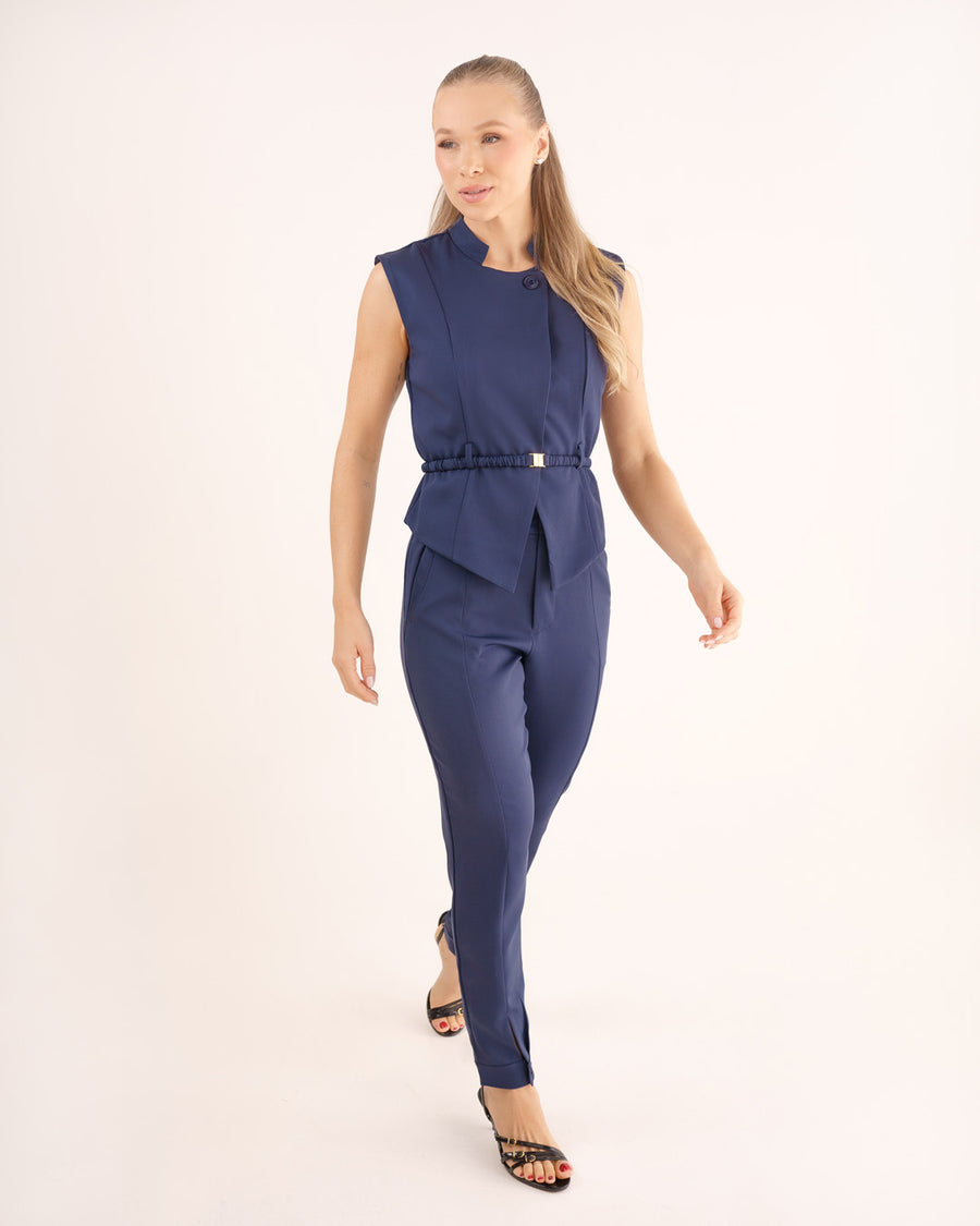 Scrub feminino Ella azul marinho, modelo caminhando de frente, blusa sem manga acinturada e calça slim azul